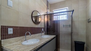 Ein Badezimmer mit zwei Waschbecken, einem Spiegel und einer Duschkabine.