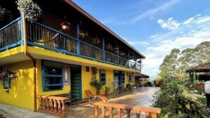 A two-story building with a balcony, a covered patio, and a pathway leading to the entrance.