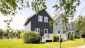 A two-story house with a dark exterior, white trim, and a small porch. - Spring Lake 43, Jesse-Belle (P) - Lakeside Holiday Lodge, Watersports, Sleeps 6 (South Cerney)