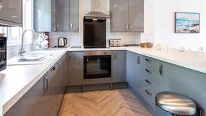 A modern kitchen with grey cabinets, a stainless steel range hood, and a herringbone wood floor. - Spring Lake 43, Jesse-Belle (P) - Lakeside Holiday Lodge, Watersports, Sleeps 6 (South Cerney)