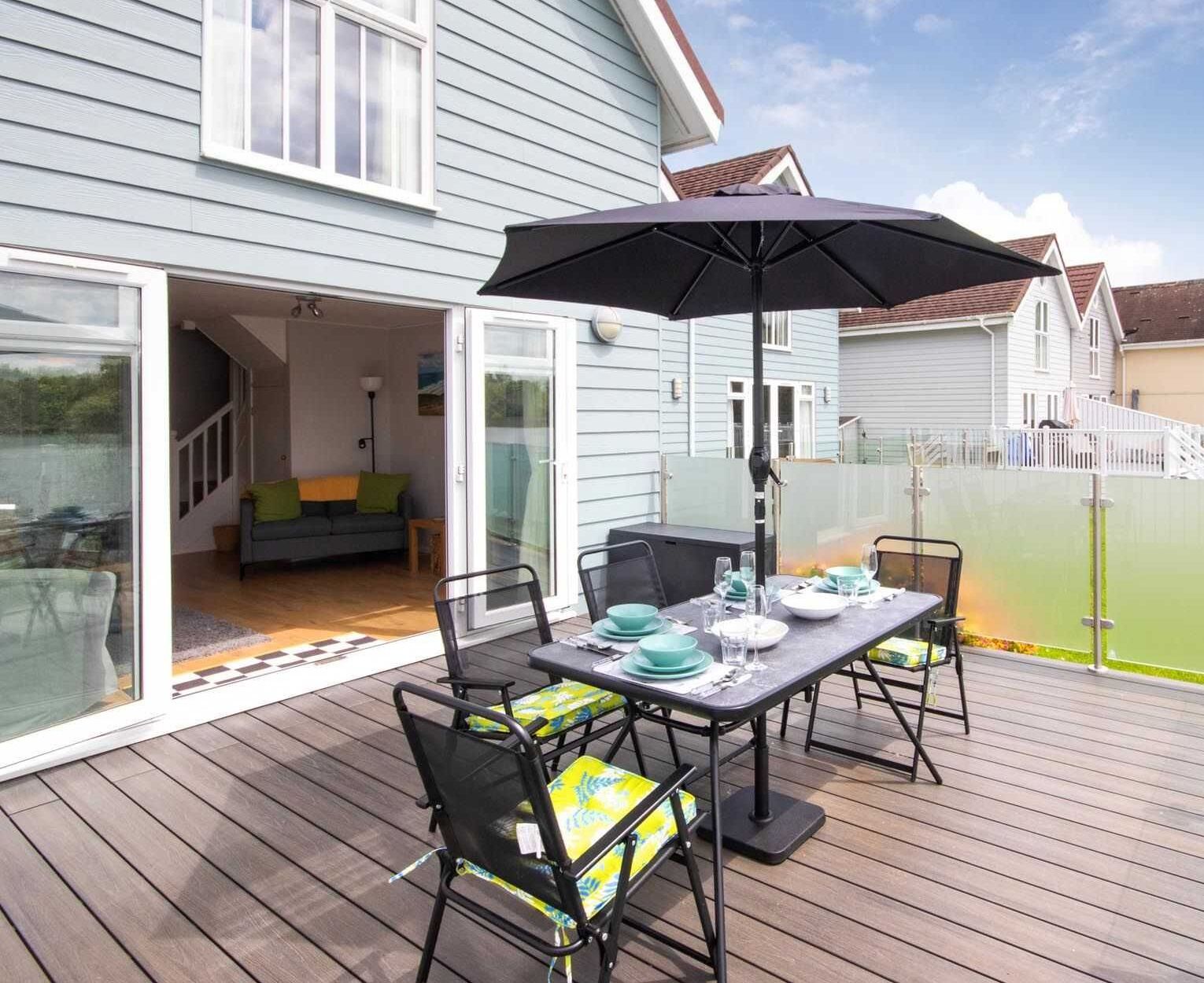A patio with a table set for dining, outdoor seating, and a covered area with an umbrella.