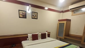 A hotel room with a bed, a bench, a wardrobe, and two wall-mounted pictures. - Span Suites by Stayz Royale (Bengaluru)