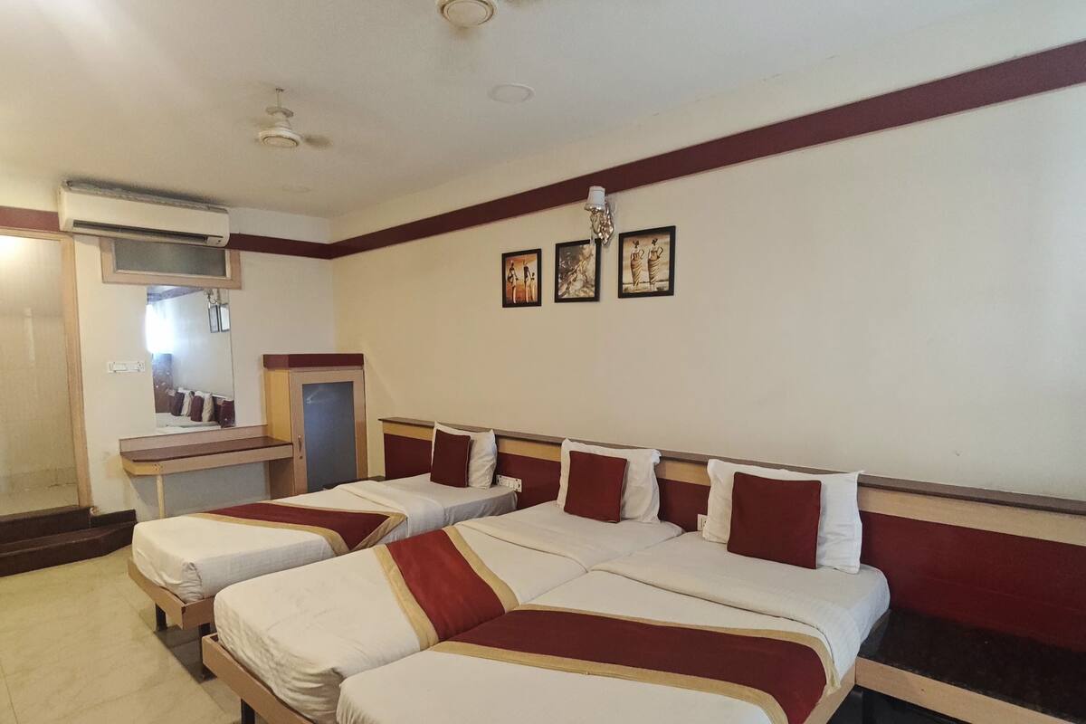 A hotel room with two beds, a mirror, an air conditioning unit, and a ceiling fan.