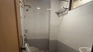 A small, basic bathroom with a toilet, a shower, and a sink. - Span Suites by Stayz Royale (Bengaluru)