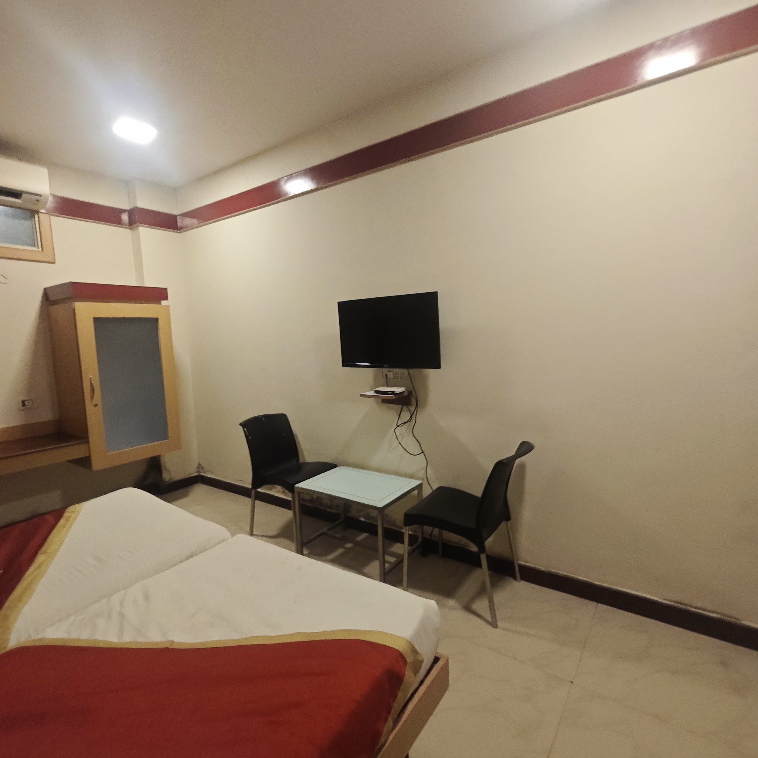 Une chambre d’hôtel comprenant un lit, un bureau, deux chaises, un téléviseur fixé au mur et une armoire.