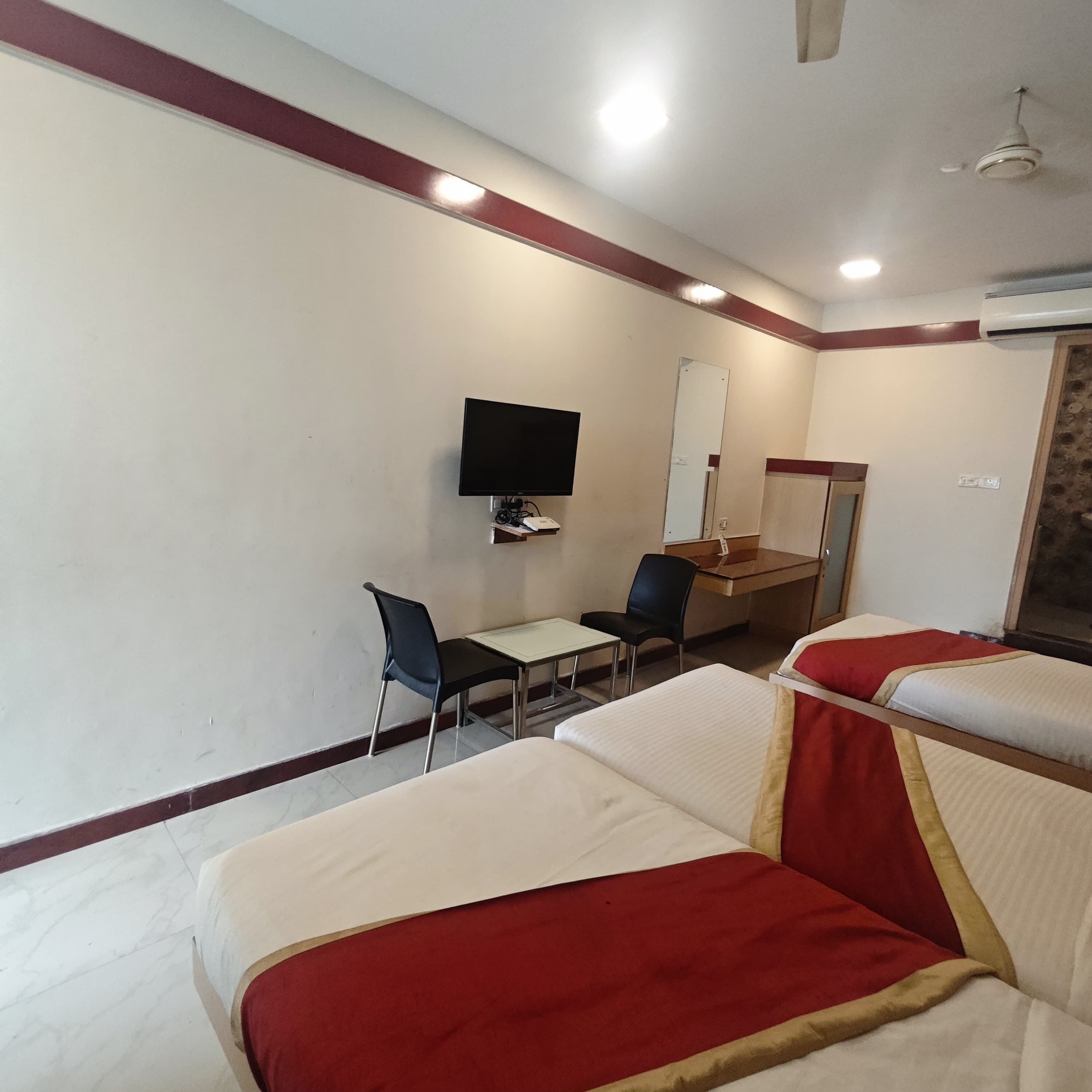 Habitación de hotel con dos camas, un escritorio, una silla, un televisor y un espejo.