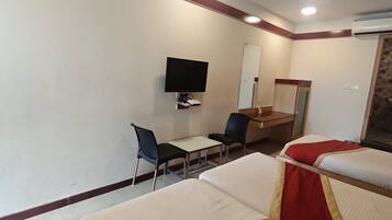 Habitación de hotel con dos camas, un escritorio, una silla, un televisor y un espejo.