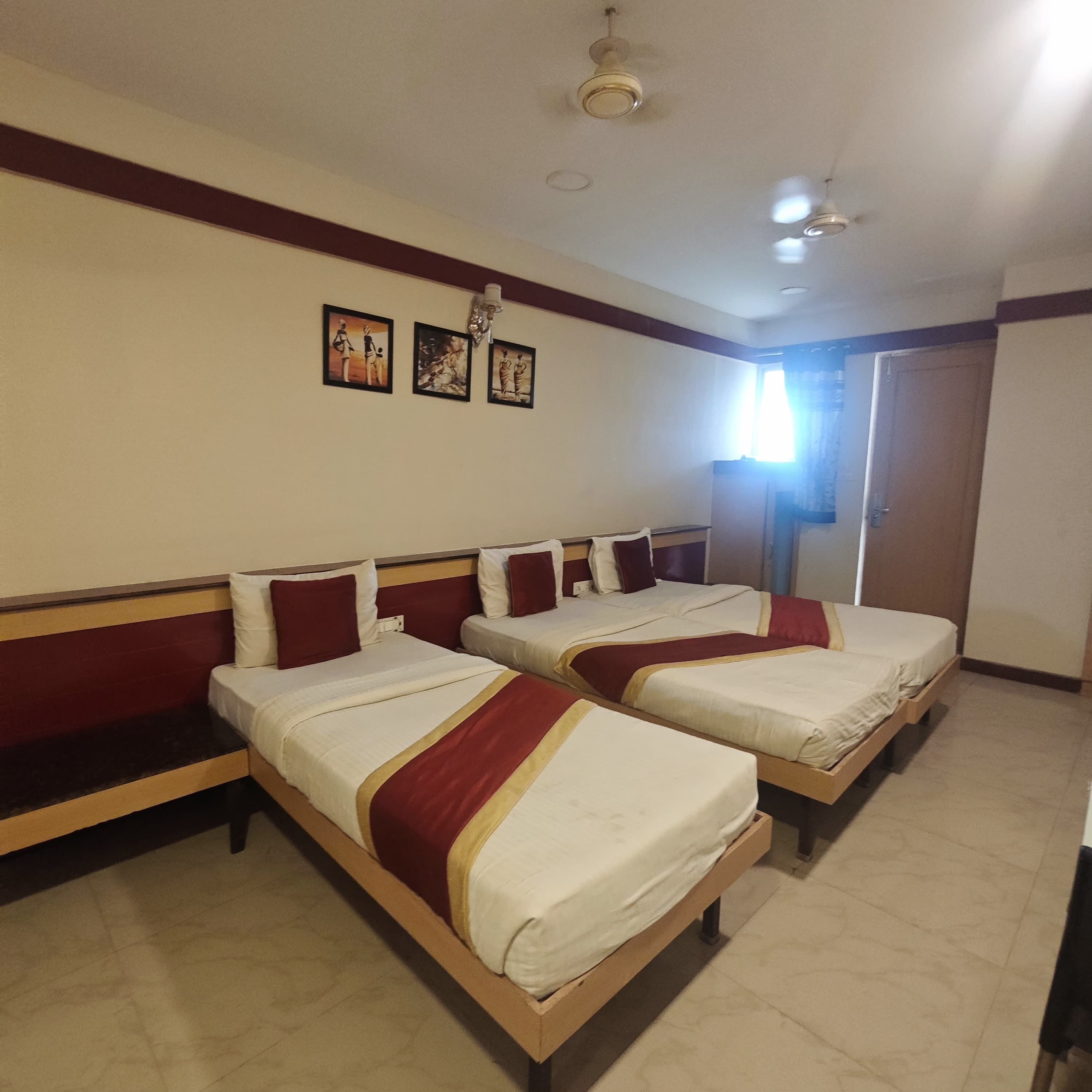 A hotel room with two beds, a ceiling fan, and wall-mounted artwork.