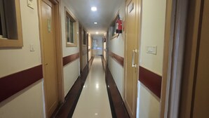 A long, narrow hallway with doors on both sides, a fire extinguisher mounted on the wall, and a light fixture on the ceiling. - Span Suites by Stayz Royale (Bengaluru)