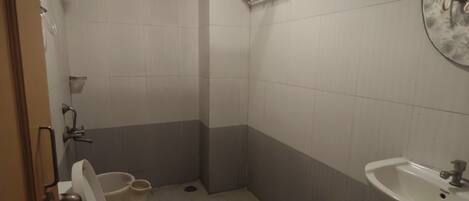 A small bathroom with a toilet, sink, and shower.