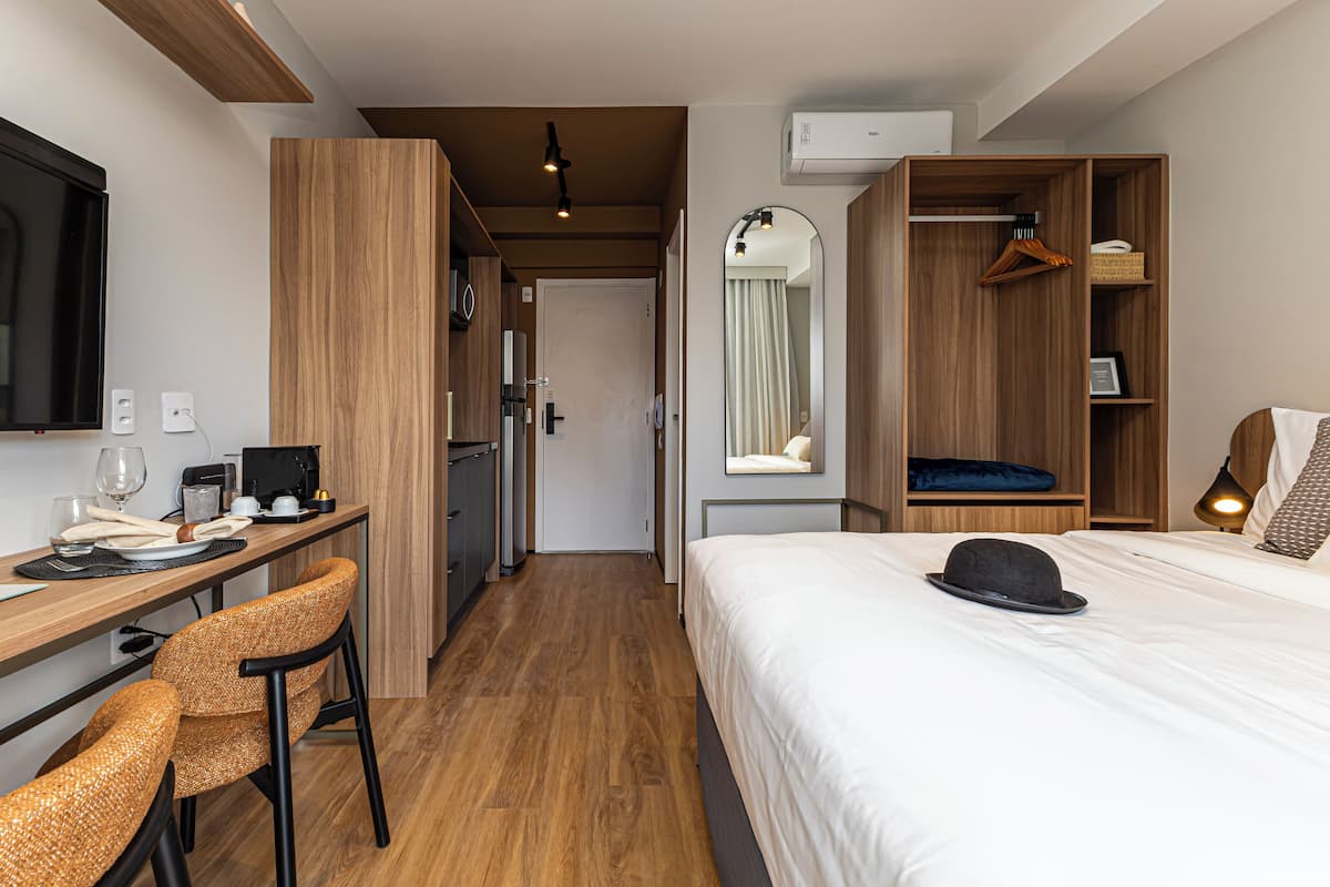 Une chambre d’hôtel comprenant un lit, un bureau avec une chaise, une armoire et un miroir.
