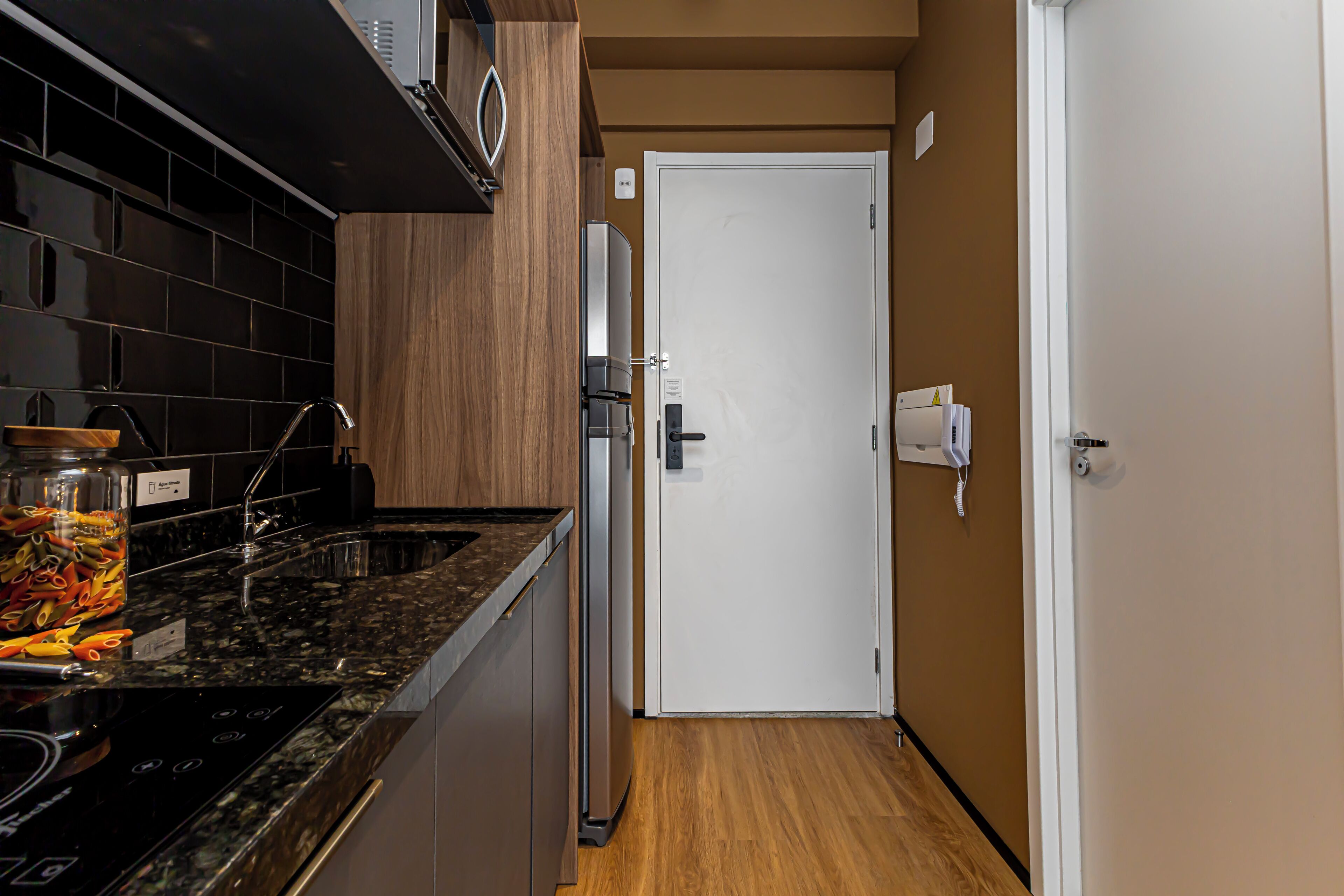 A kitchen with a black countertop, stainless steel appliances, and a wooden cabinet.