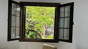 Une pièce comprenant une table à manger, une chaise et une fenêtre donnant sur un arbre et des rochers.