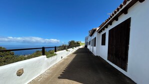 Un couloir avec un mur blanc, des volets noirs et une rambarde noire.