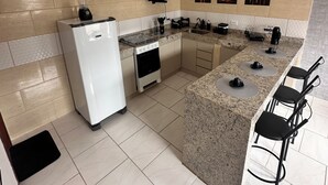 A modern kitchen with a built-in stove, microwave, and blender, a granite countertop, and a bar area with stools.