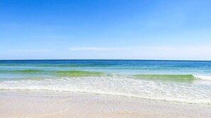 A beach with clear blue water and a sandy shore.