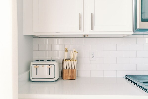 A kitchen with white cabinets, a white toaster, and a knife block on the counter.