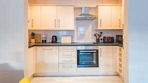 A modern kitchen with white cabinets, a built-in oven, and a countertop with various appliances.