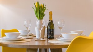 A dining table set with white bowls, wine glasses, and a bottle of champagne.