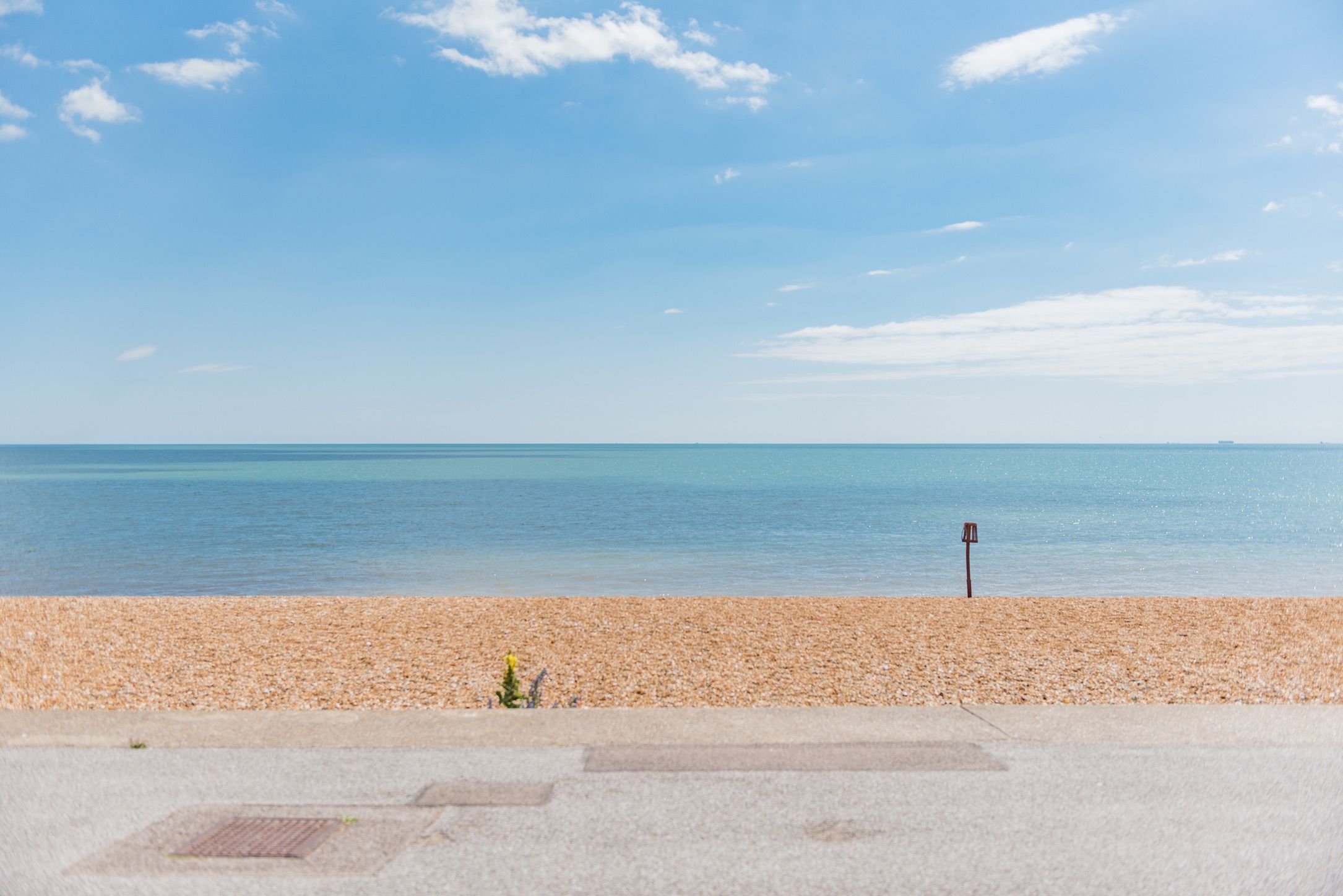 A pebbled beach with a clear sky and calm sea.