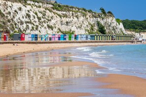Une plage avec des cabanes de plage aux couleurs vives et un rivage sablonneux.