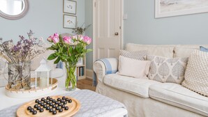 A cozy living room with a white sofa, a small table with a candle, and a vase of pink roses. - Michaelmas Cottage, Broadstairs (Broadstairs)