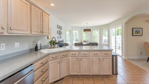A spacious kitchen with a large island, wooden cabinets, and a view of the outdoors through large windows. - Private & Spacious - Near JMU & Massanutten - Grill + Firepit - Sleeps 10 (Penn Laird)