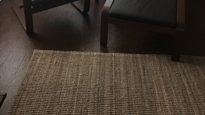 Deux fauteuils avec des coussins rouges, une petite table et une lampe sur pied dans une pièce dotée d’une fenêtre.