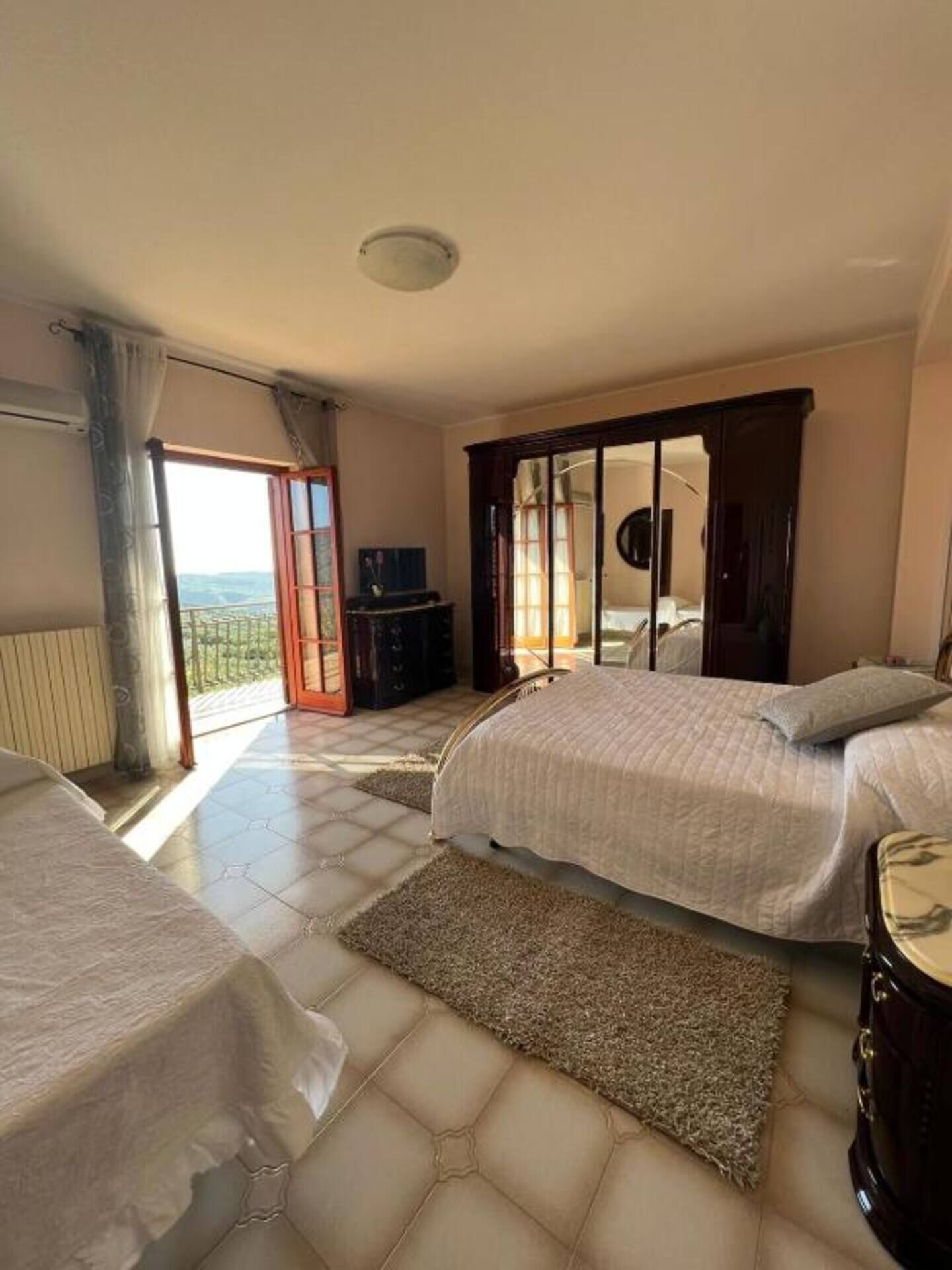 Ein Schlafzimmer mit zwei Betten, einem Kleiderschrank, einem Fernseher und Blick ins Freie.