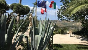 Una estatua en un jardín con cielo despejado y colinas al fondo.