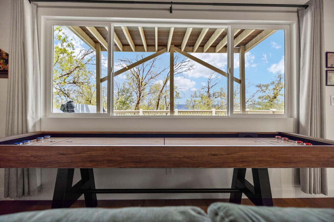 Ein Billardtisch mit Blick auf Bäume und einen klaren Himmel durch ein großes Fenster.
