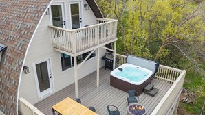 Een tweelaags huis met een terras, een hottub, buitenmeubilair en een vuurkuil.