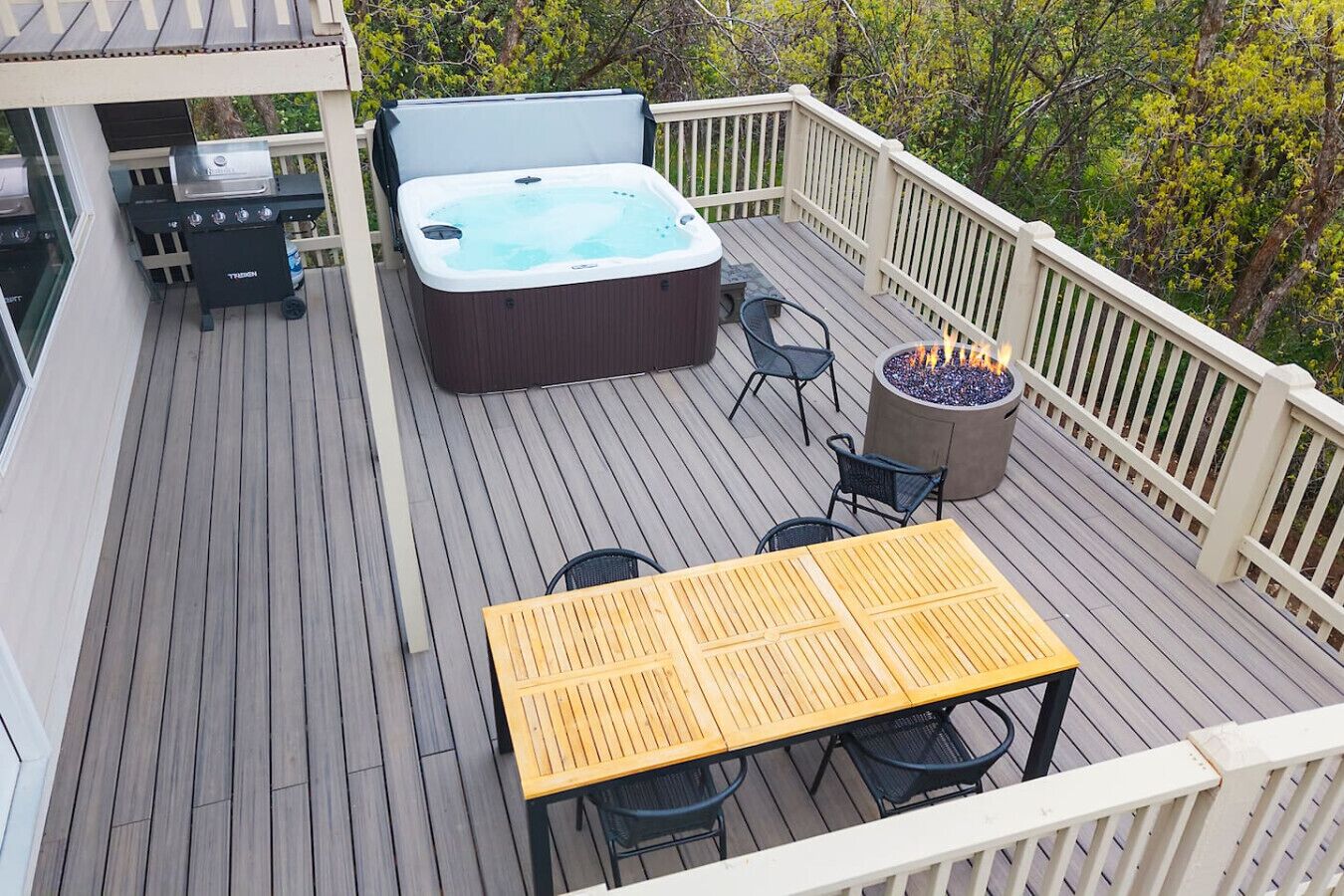 A deck with a hot tub, a fire pit, and outdoor seating.