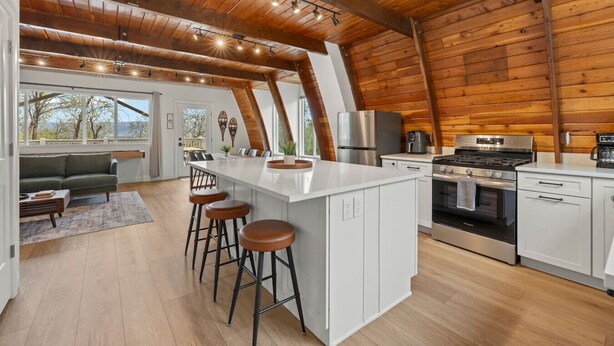 Een moderne keuken met een centraal eiland, barstoelen en een zithoek met een bank en tafel.