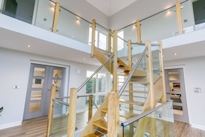 A modern interior with a central spiral staircase, glass railings, and a wooden finish.