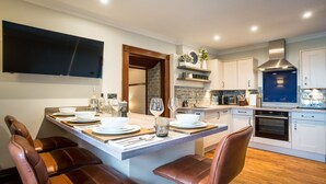 A modern kitchen with a central island, white cabinetry, and a built-in oven.