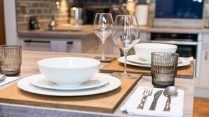 A modern kitchen with a wooden countertop, white plates, bowls, and clear glassware.