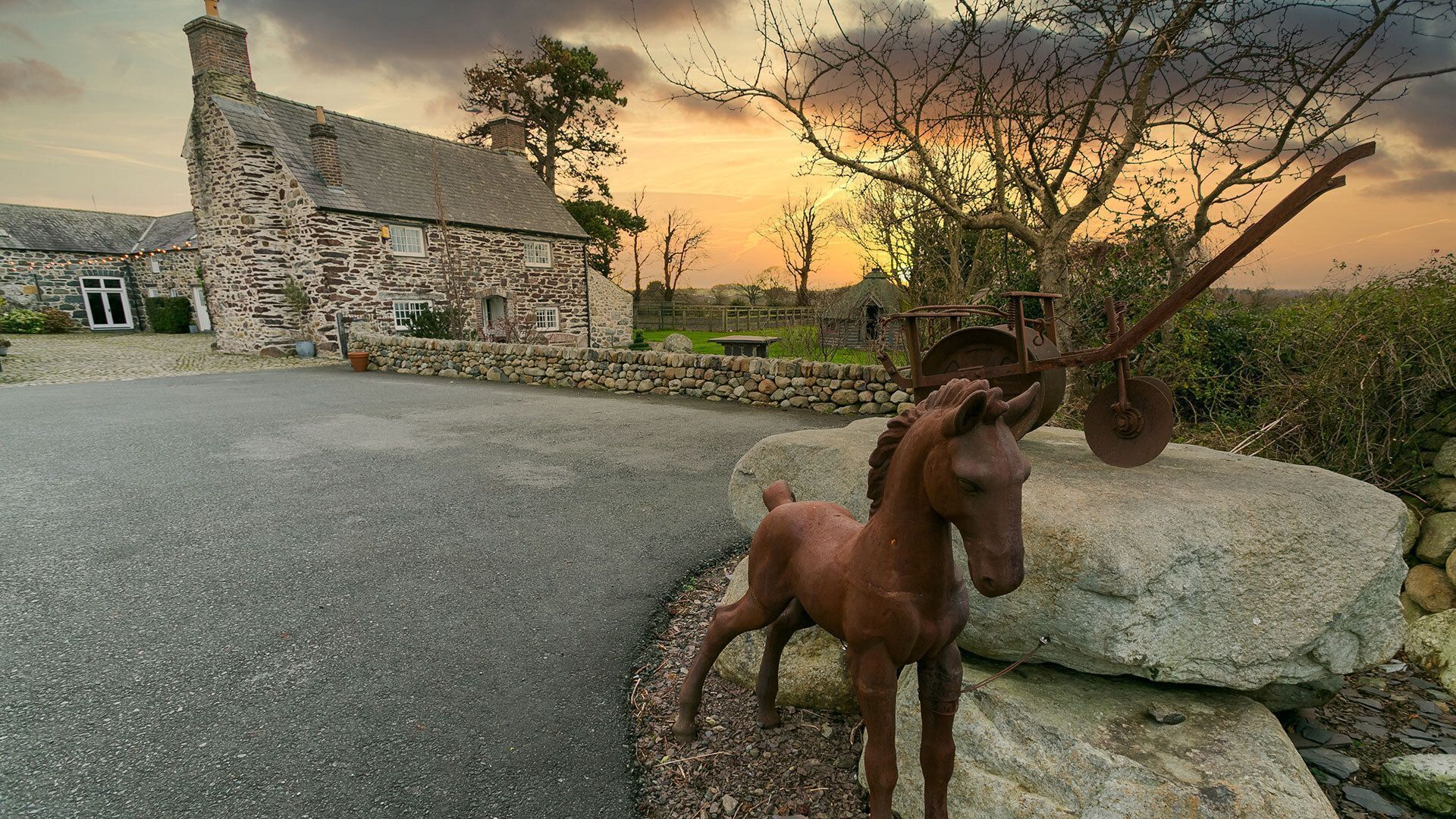 Un edificio de piedra con una gran roca y una estatua de caballo de metal al frente.