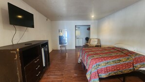 A bedroom with a bed, a TV, a desk, and a chair. - Bay Inn (Dickinson)