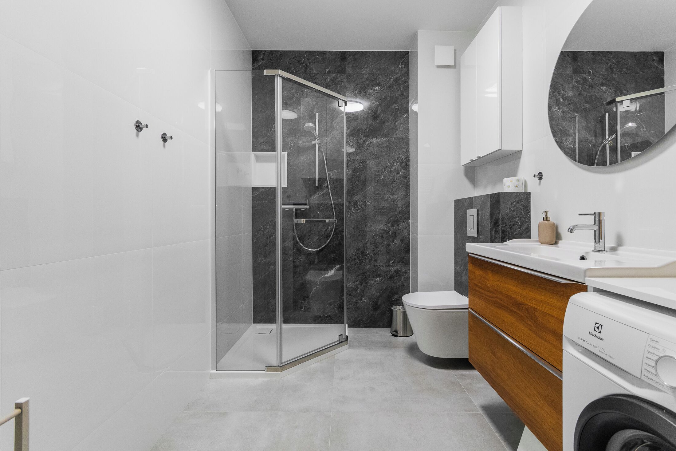 Une salle de bain moderne avec une douche à parois de verre, des toilettes et un lave-linge.