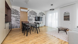 A modern living space with a dining area, a flat-screen TV, and a cozy seating area. - Perła Mierzei by Grand Apartments (Sztutowo)