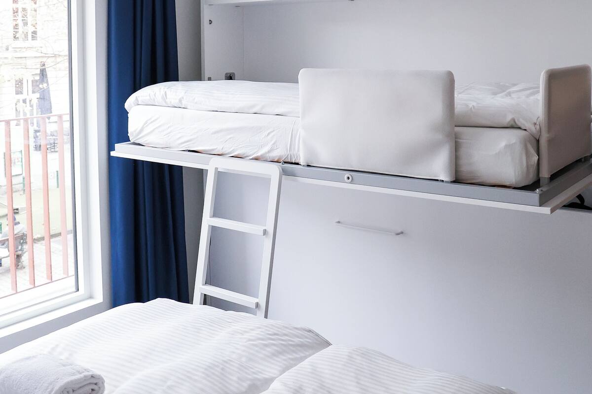Ein Zimmer mit Etagenbett, Schreibtisch und einem fenster mit Vorhängen.