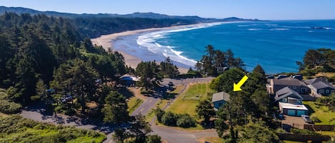 Luftaufnahme einer Küstenregion mit Strand, Häusern und einer Straße.