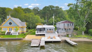 Una propiedad frente al lago con un muelle, una casa con balcón y un bote.