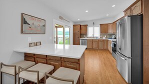 Una cocina moderna con armarios de madera, un refrigerador de acero inoxidable y una isla grande con taburetes de bar.