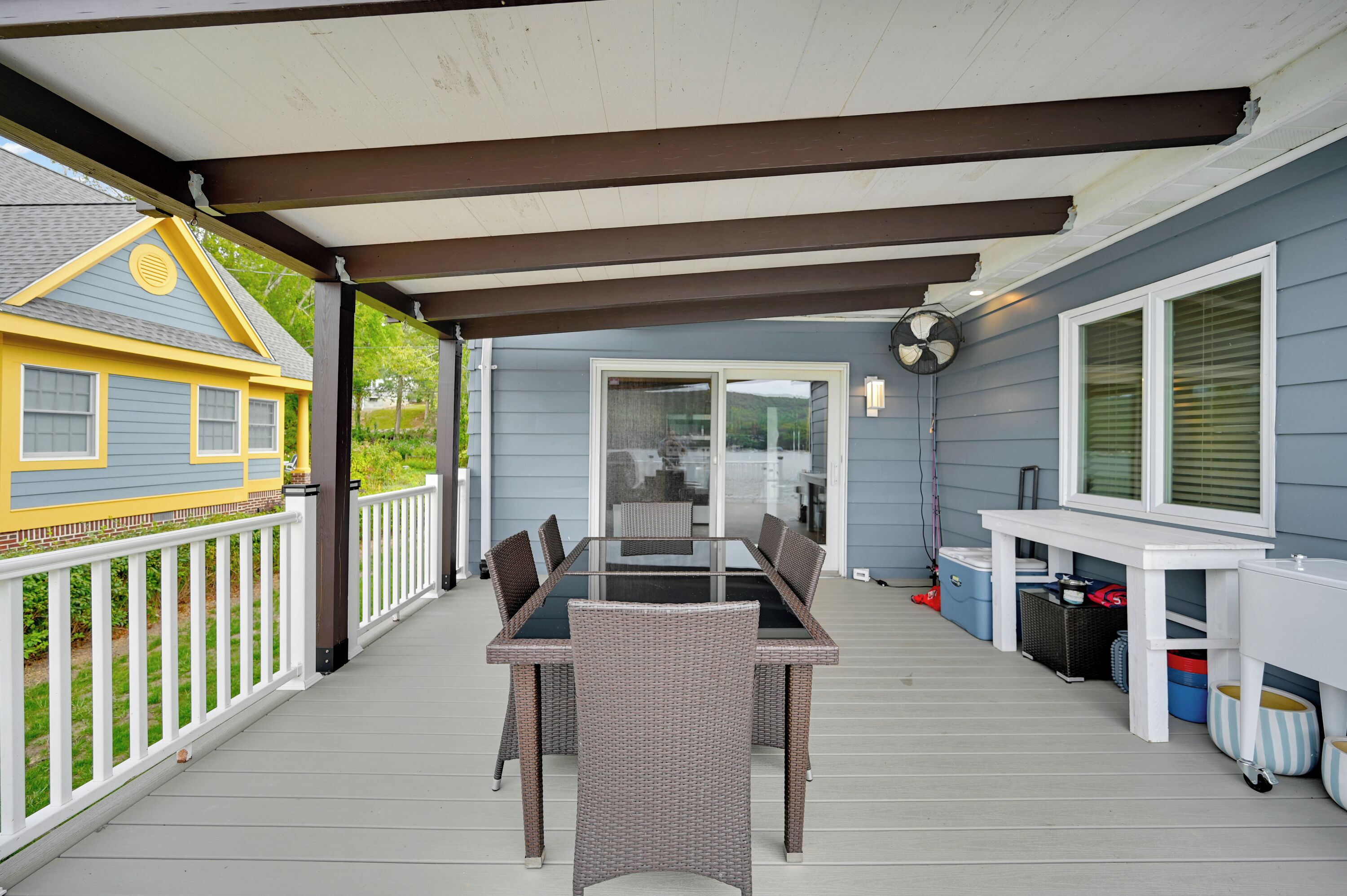 A covered patio with a dining table and chairs, a ceiling fan, and storage cabinets.