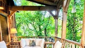 Eine Holzterrasse mit Sitzgelegenheiten im Freien, darunter eine Couch und Stühle sowie ein Tisch mit Unterlage.
