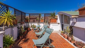 A rooftop terrace with two lounge chairs, potted plants, and a lattice fence. - One Bedroom Apartment (ROMA)