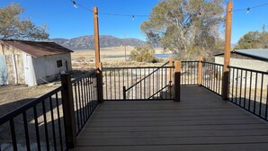 A wooden deck with a metal railing, leading to a rustic building with a corrugated metal roof.