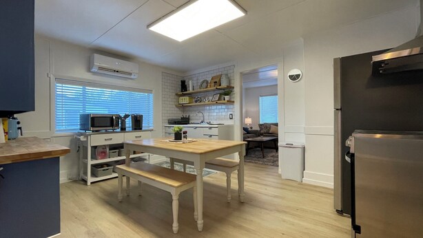 A modern kitchen with a dining area, wooden furniture, and a built-in microwave.